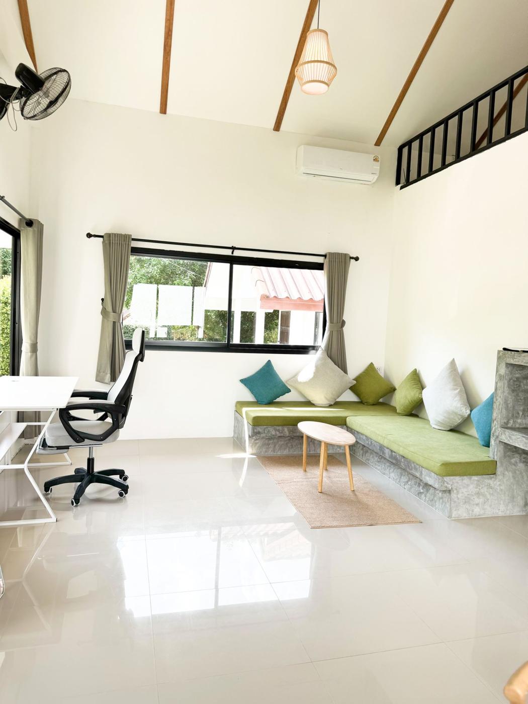 Bright living room with built-in sofa, work desk and high ceiling
