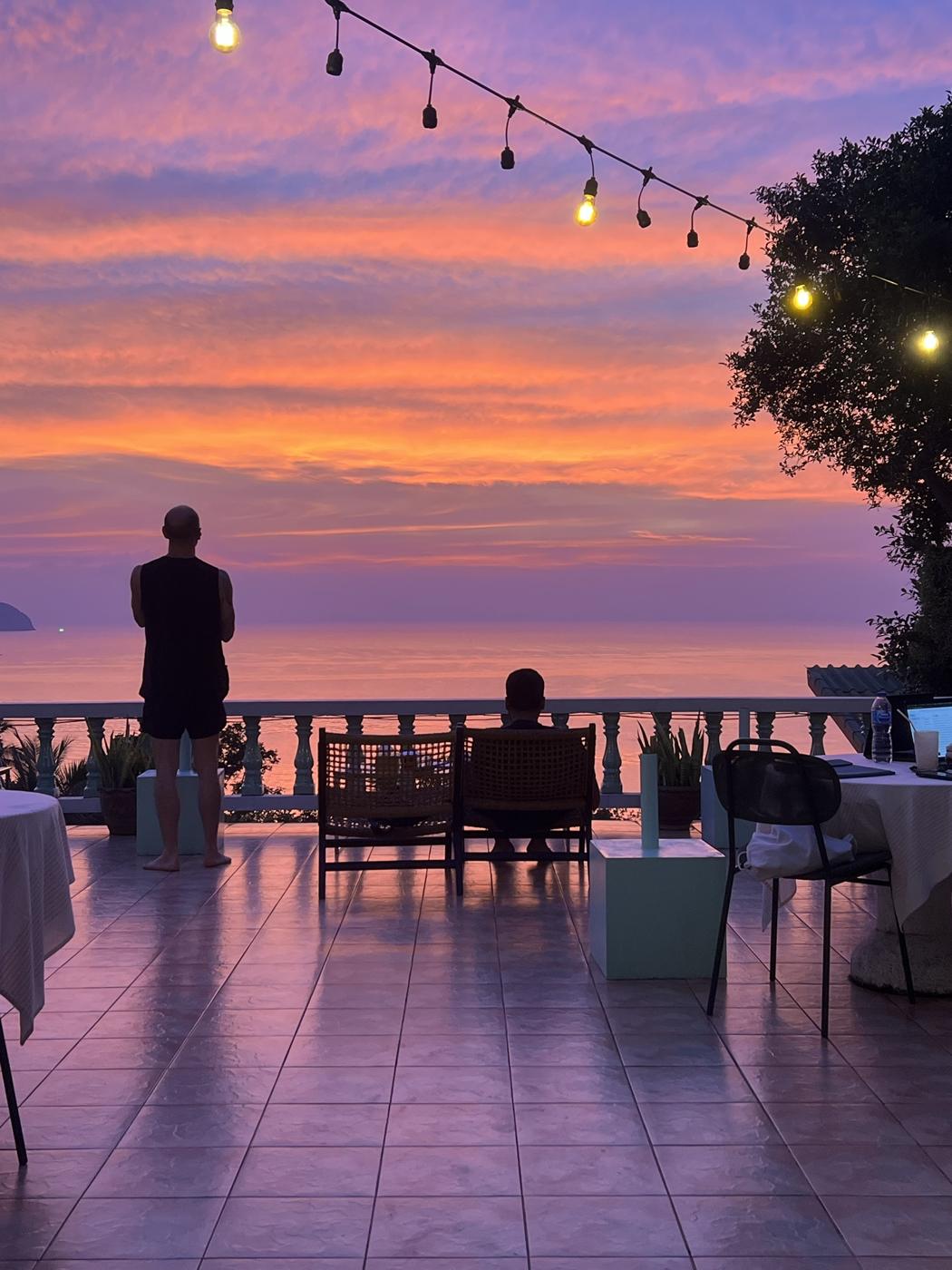 Pink and orange sky over the Mille terrace with string lights