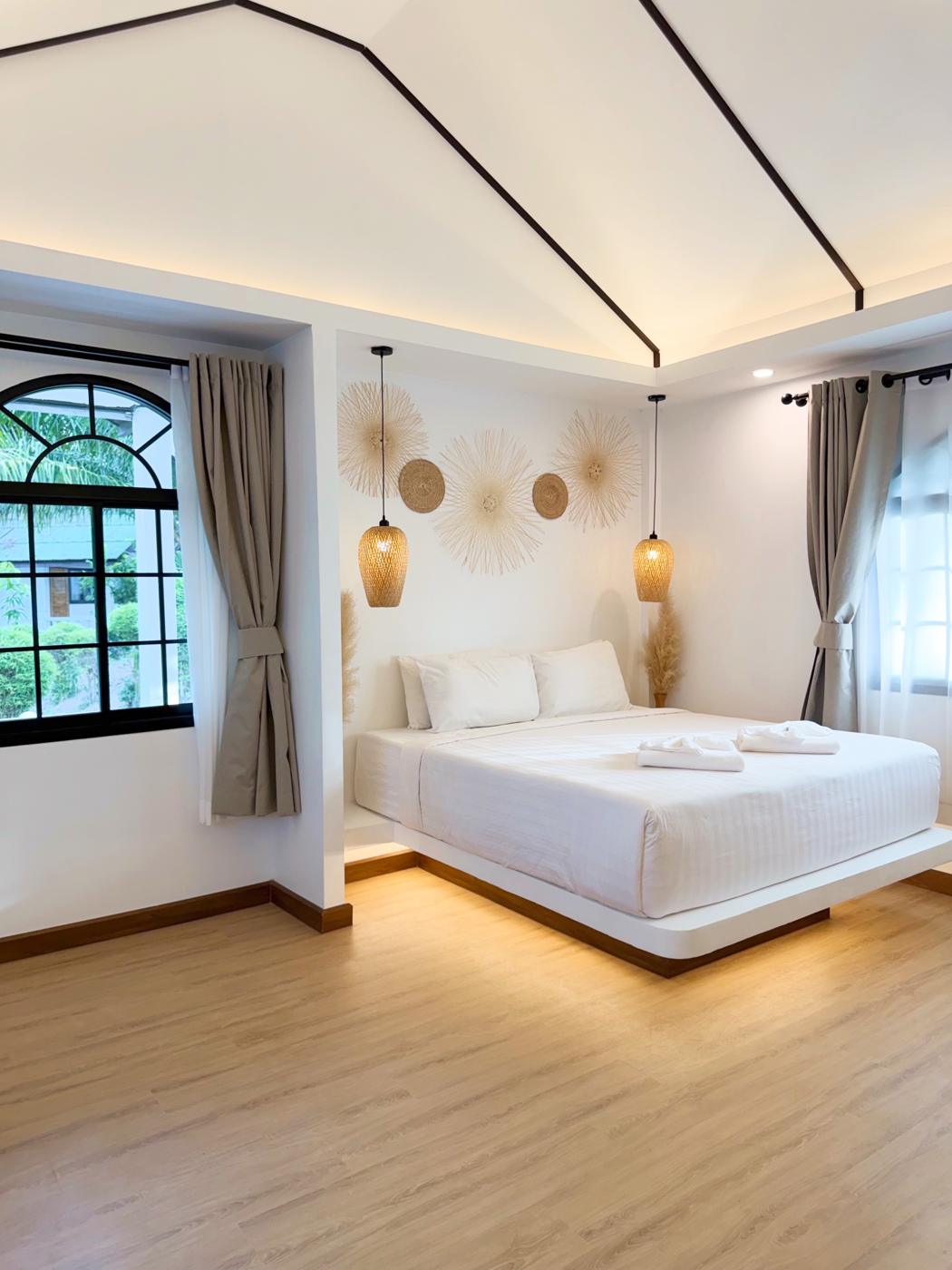 Floating white bed under woven pendant lights