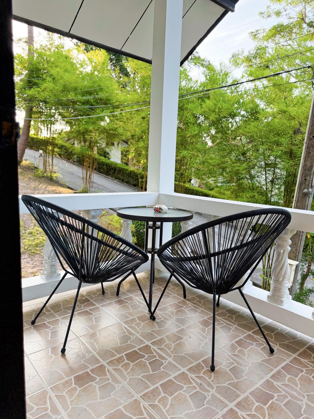 Balcony with two chairs and a small table above the garden
