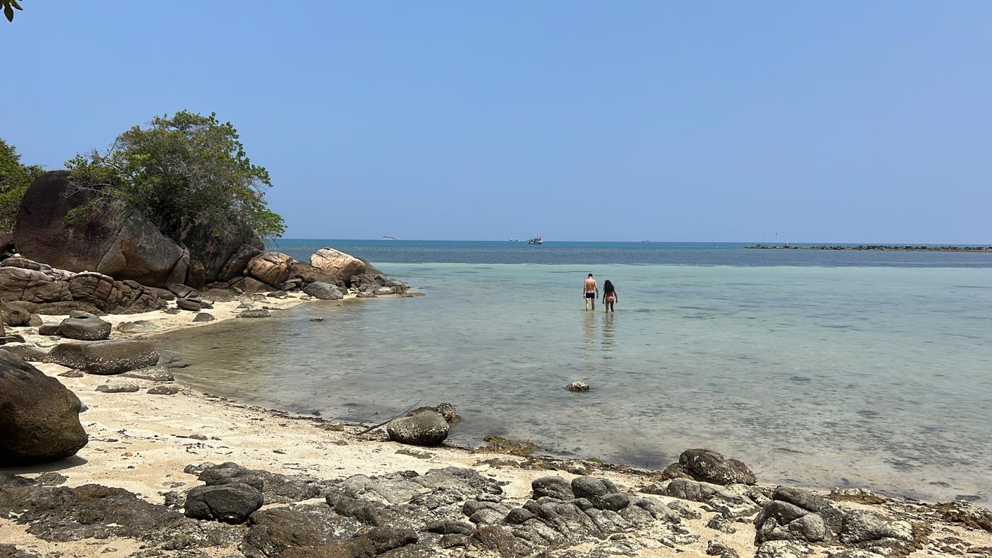 Couple wading into clear shallow water at a rocky beach